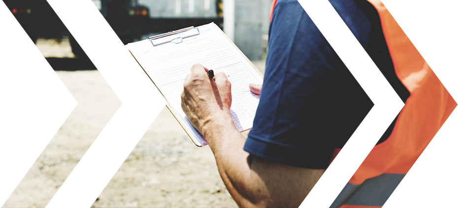 Construction worker in a reflective vest writing on a clipboard.
